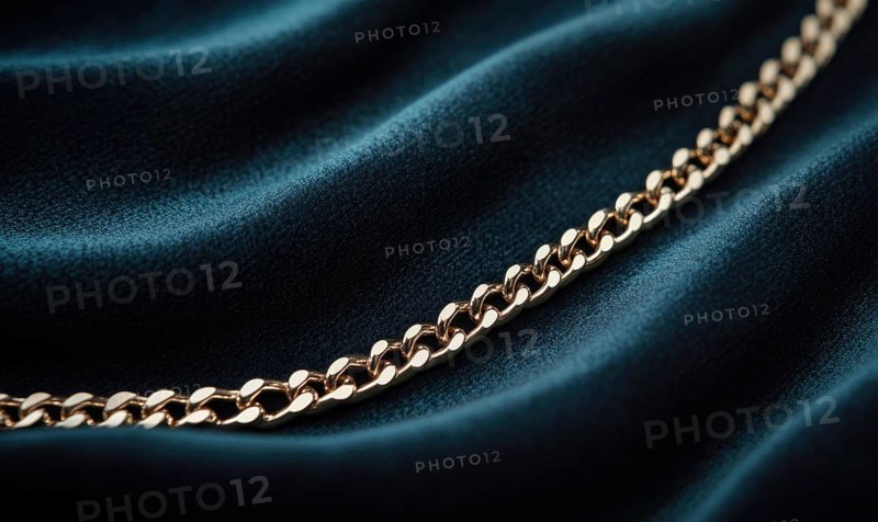 A gold chain necklace is on a blue velvet background. The necklace is made of gold and has a chain design AI generated