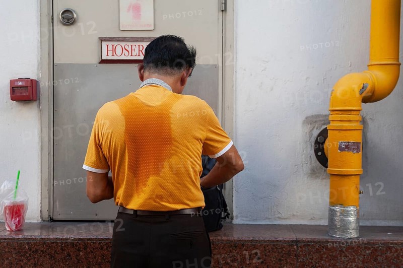 01/02/2019, Singapore, Republic of Singapore, Asia, Rear view of a man with a sweaty T-shirt standing next to a downpipe in Chinatown, Asia
