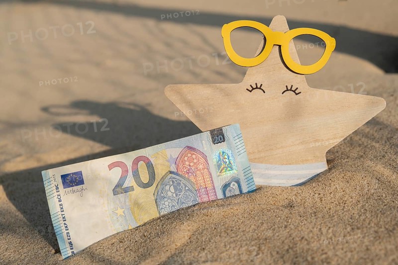Money 20 euros bills in sandy beach with starfish. Concept finance saving money for holiday vacation. Costs in travel holidays. Shadows