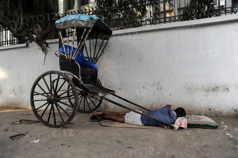 25.02.2011, Kolkata, West Bengal, India, Asia, A rickshaw driver sleeps next to his wooden rickshaw on a roadside in Kolkata, the only city in India where hand-pulled rickshaws still exist, Asia