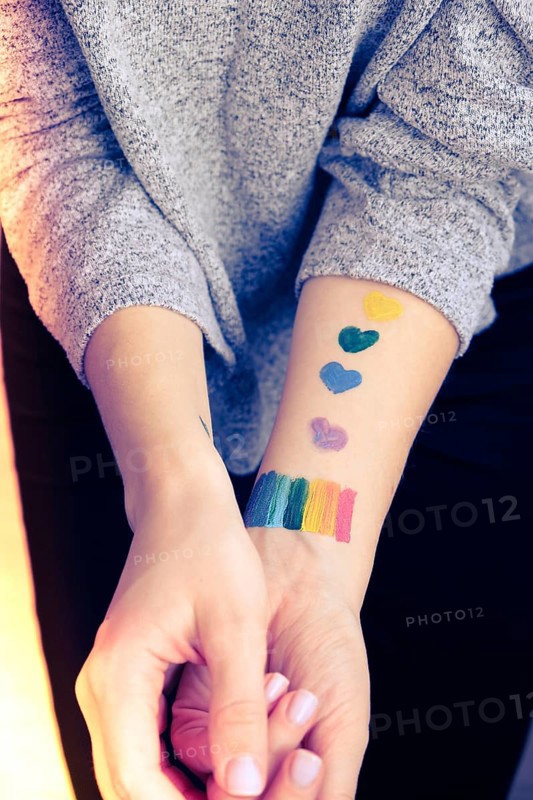 Rainbow LGBTQ flag painted on hand. Support for lgbt community. Honour of pride month. Connecting people, touching hands. Multi colored hands art creativity, discrimination. Selective focus