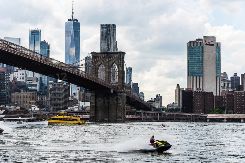 New York City, USA, June 24, 2018: Cityscape of Downtown of Manhattan and Brooklyn Bridge with jet ski and tour boats navigating on East River, North America
