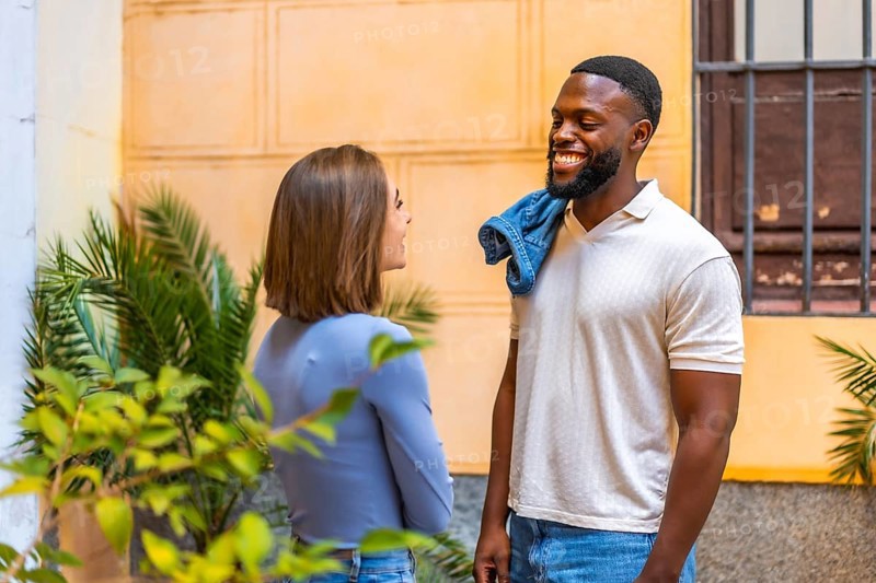 Multi-ethnic african and caucasian couple talking relaxed and smiling in the street