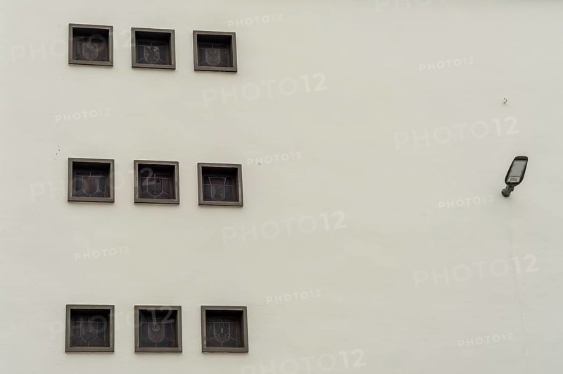 Nine square windows adorn a white wall with a lamp on the right-hand side