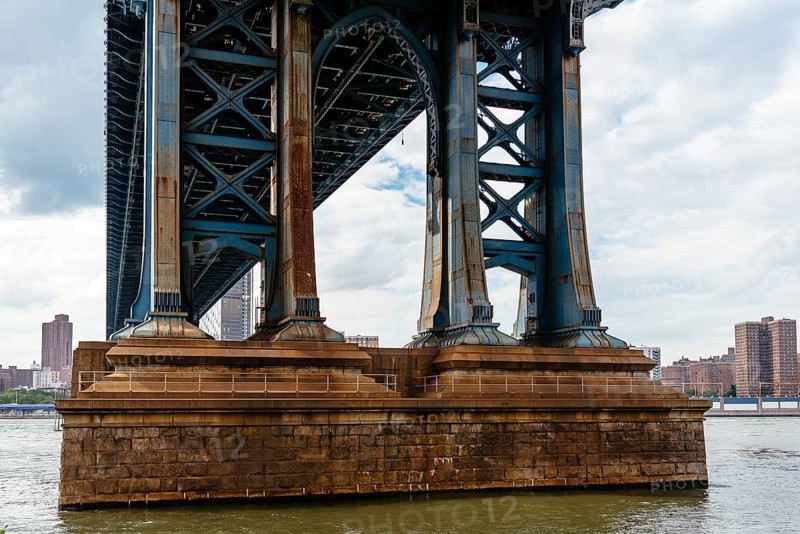 Detail of Pillar of Manhattan Bridge against cityscape of New York City. Steel Abutment With Bolt and Rivet Connections. Engineering and architecture