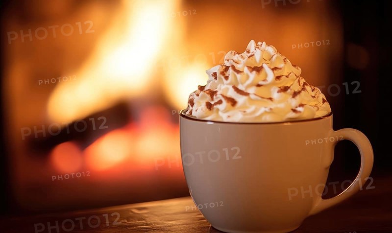 A cup of hot chocolate with whipped cream on top sits on a wooden table next to a fireplace. The scene conveys a cozy and warm atmosphere, perfect for enjoying a hot beverage on a cold day AI generated