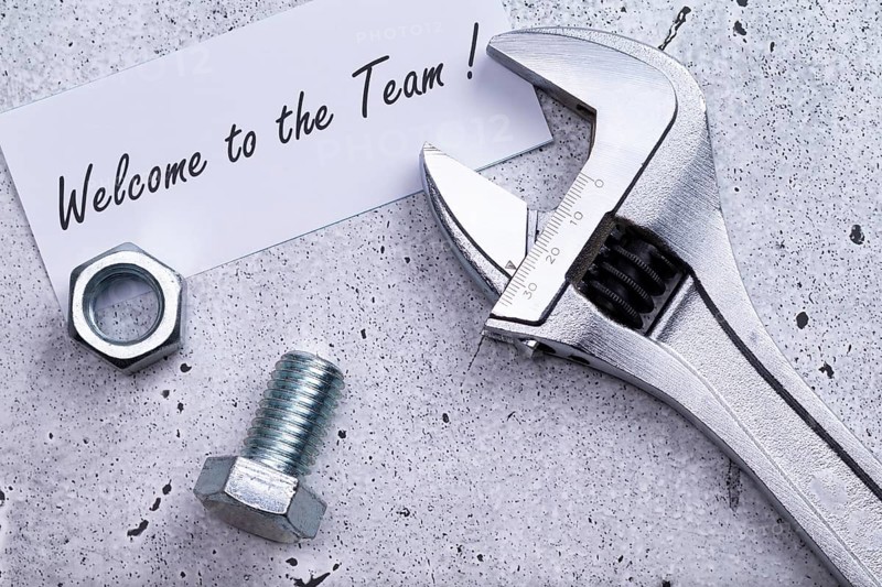 The photo shows a label with the inscription 'welcome to our team' with a spanner and screw on a grey background