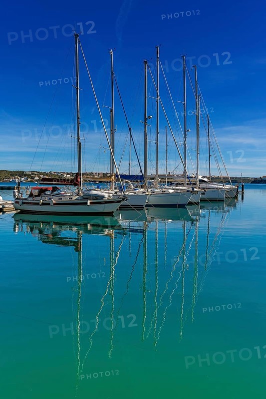 Mahon, Spain, 24 January, 2024: vertical view of moored sailboats in the harbour of Mahon on Menorca with reflections in the turquoise water, Europe