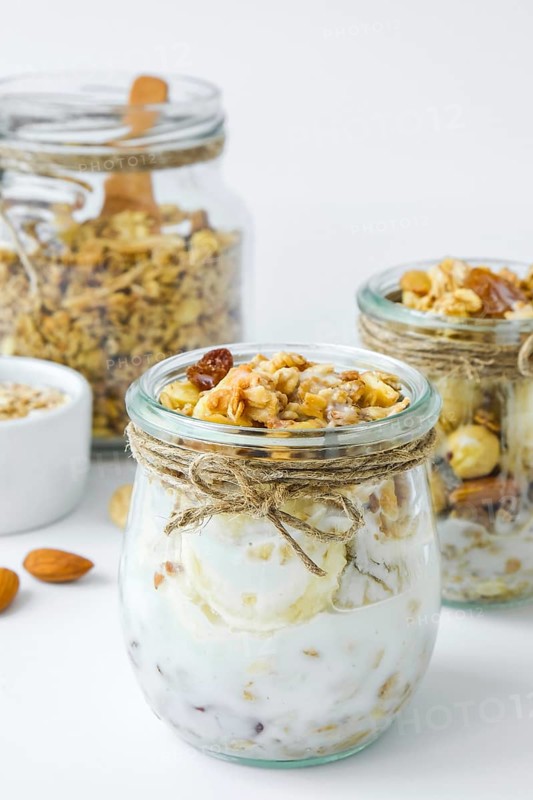 Healthy breakfast. Oatmeal Granola with greek yogurt and nuts banana muesli in jars on light background. Vegan, vegetarian and weight loss diet concept. Detox menu. Healthy eating food