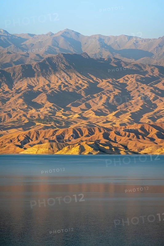 Blue Toktogul reservoir between dry mountain landscape, hilly mountains in the evening light, Jalalabad region, Kyrgyzstan, Asia
