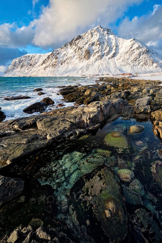 Beach of Norwegian sea on rocky coast in fjord on sunset in winter. Vareid beach, Lofoten islands, Norway, Europe