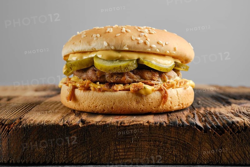 Beef burger with pickled cucumber and onion crumbs front view
