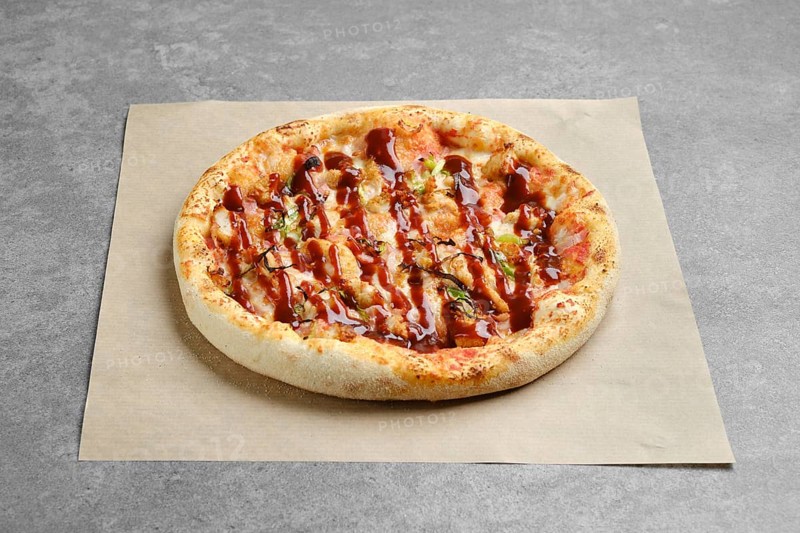 Barbecue pizza with bacon and spring onion on parchment paper