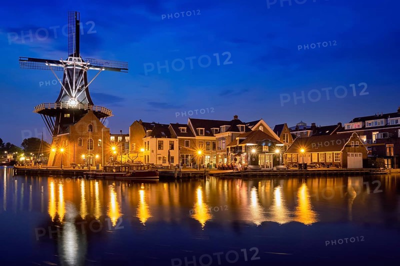 View of Harlem cityscape with landmark windmill De Adriaan on Spaarne river in the night illuminated. Harlem, Netherlands