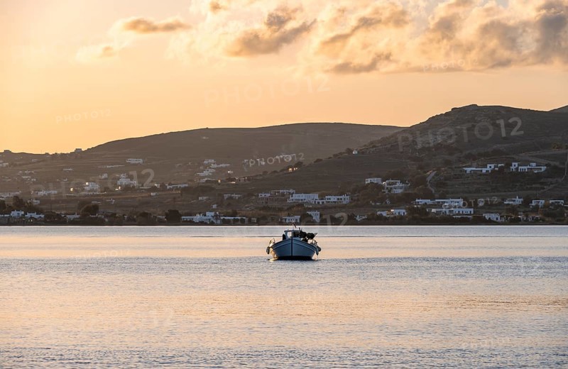 Fishing boat on the sea, behind hill of Paros island, Naoussa, Paros, Cyclades, Greece, Europe