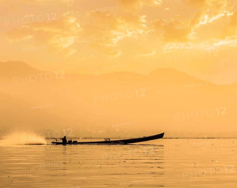 Speeding motor boat silhouette on Inle lake on sunset, Myanmar, Asia