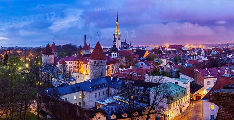Panorama of aerial view of Tallinn Medieval Old Town with St. Olaf's Church and Tallinn City Wall illuminated in twilight, Estonia, Europe