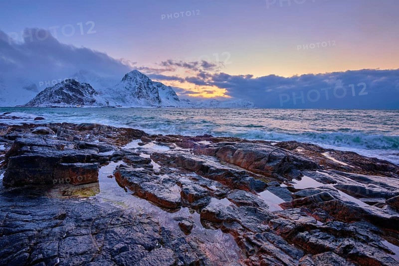 Beach of Norwegian sea on rocky coast in fjord on sunset in winter. Vareid beach, Lofoten islands, Norway, Europe