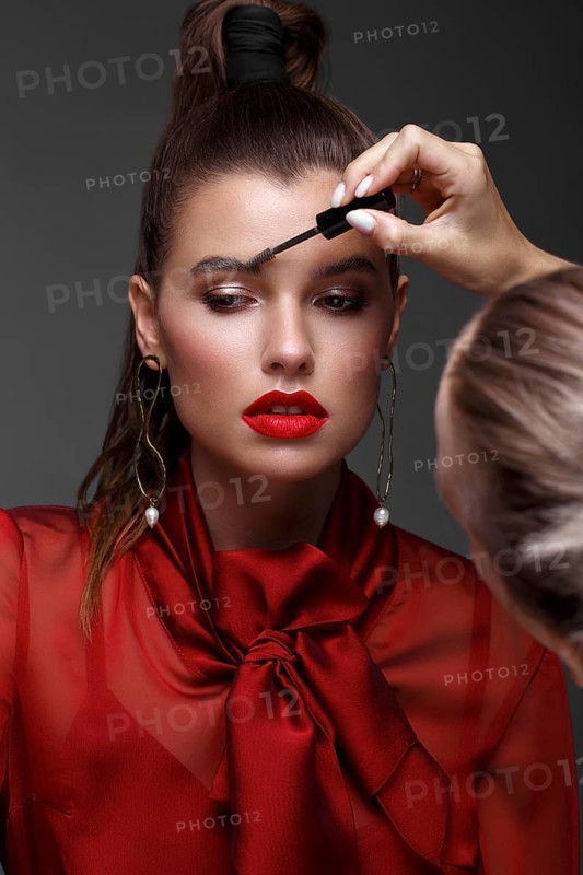 Beautiful fresh girl with classic make-up, smooth hair in a red dress. Beauty face. Photo taken in studio