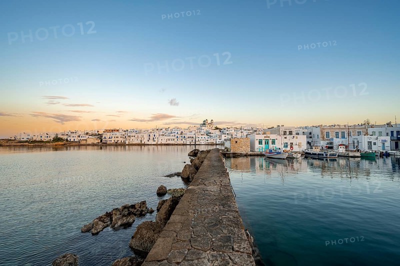 Harbour wall, view of the town of Naoussa and blue sea, at sunset, harbour with fishing boats and reflection, white Cycladic houses and church of Agios Faneromeni, Paros, Cyclades, Greece, Europe