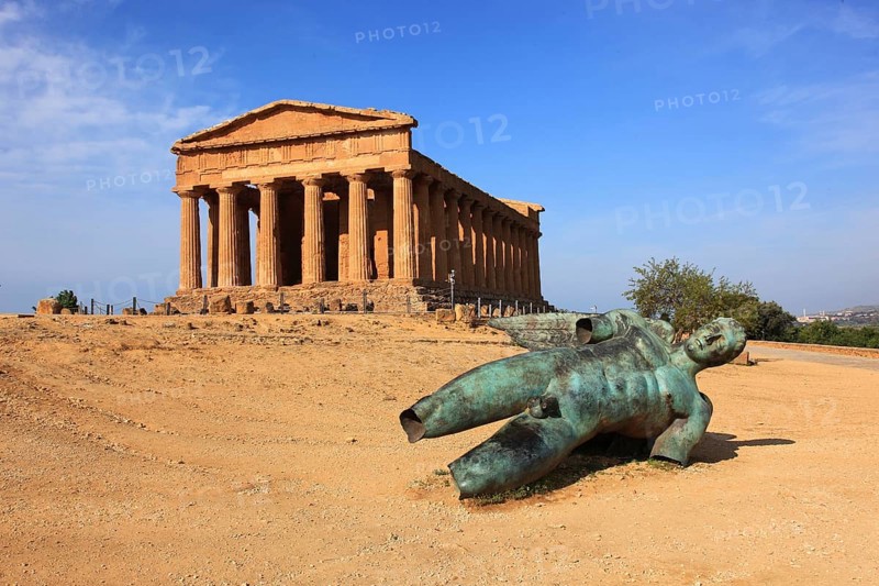 In the Parco Valle dei Templi di Agrigento, Unesco World Heritage Site, remains of the ancient city of Akragas in the Valley of the Temples of Agrigento, the Temple of Concordia with the sculpture of the crashed Icarus by the artist Igor Mitorgi, Sicily, Italy, Europe