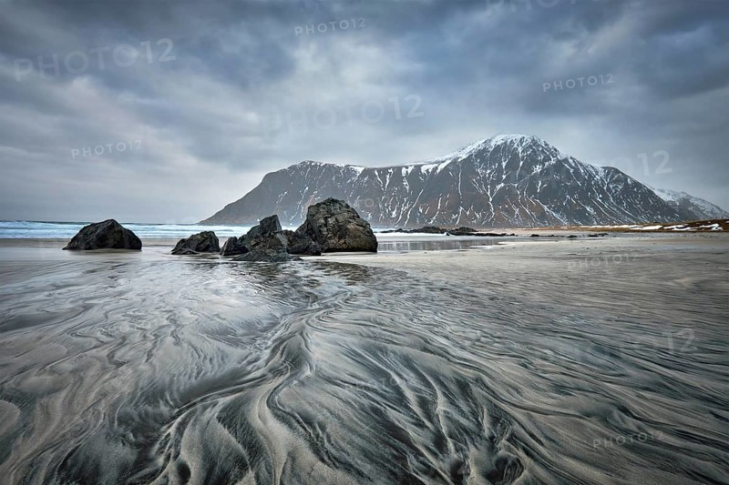 Rocky coast of fjord of Norwegian sea in winter with snow. Skagsanden beach, Lofoten islands, Norway, Europe