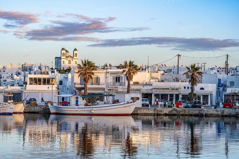 View of Naoussa, Fishing boats in the harbour at sunset, reflected in the sea, White Cycladic houses and church Agios Faneromeni, Naoussa, Paros, Cyclades, Greece, Europe