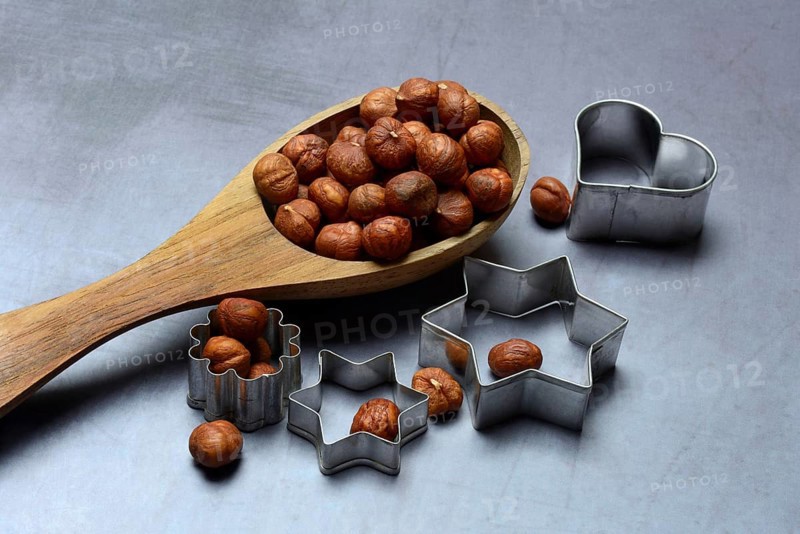 Wooden ladle with hazelnuts, cookie cutters, baking ingredient