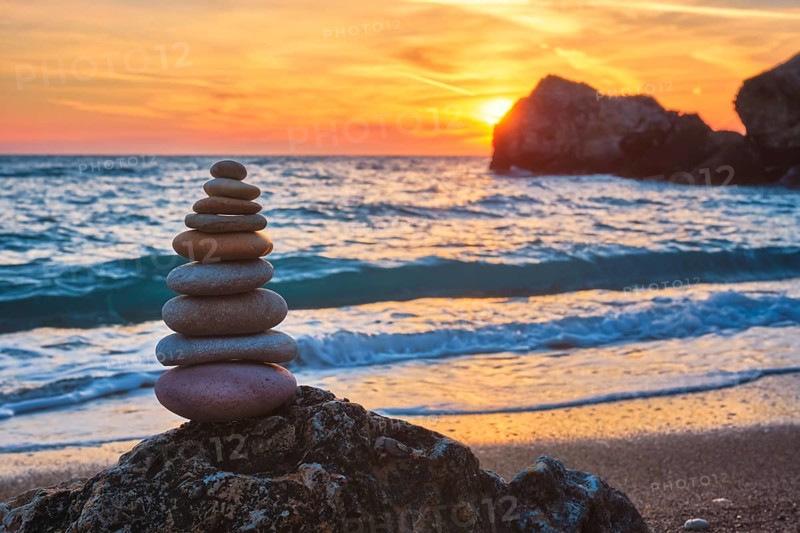 Cairn stack of stones pebbles cairn on the beach coast of the seaon sunset. Agios Ioannis beach, Milos island, Greece, Europe