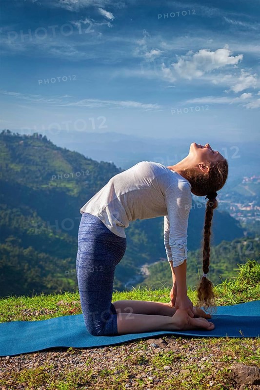 Yoga, outdoors young beautiful slender woman yoga instructor doing camel pose Ustrasana asana exercise outdoors in mountains in the morning