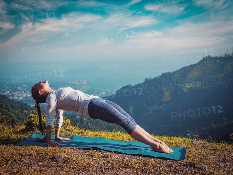 Woman doing Hatha yoga asana Purvottanasana plank pose outdoors in mountains. Vintage retro effect filtered hipster style image