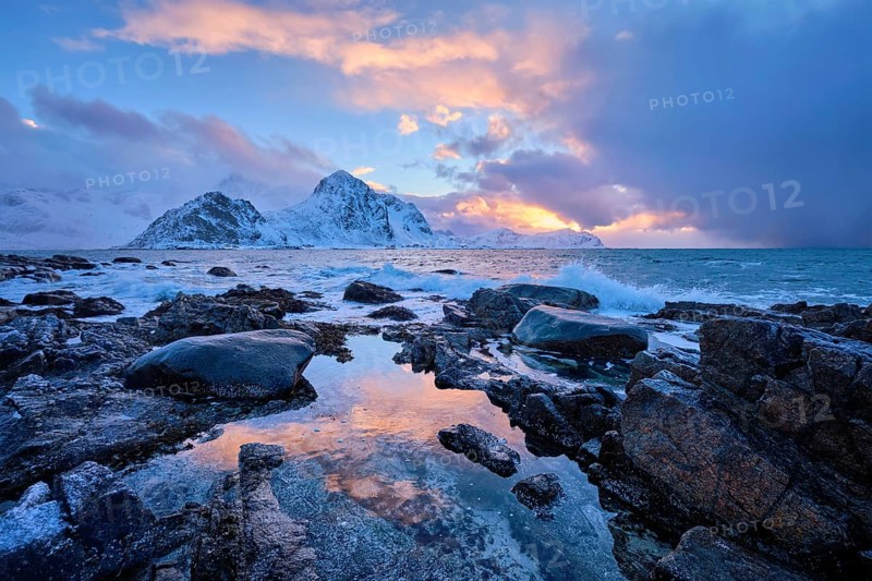 Beach of Norwegian sea on rocky coast in fjord on sunset in winter. Vareid beach, Lofoten islands, Norway, Europe