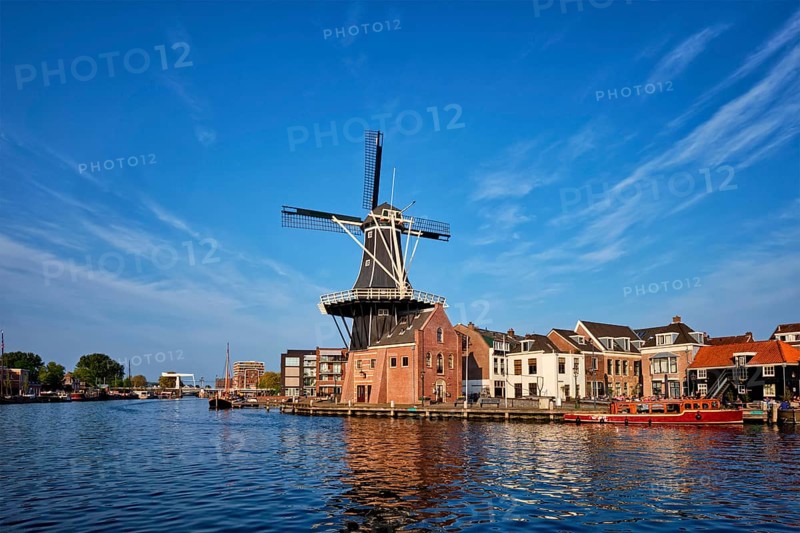 Harlem cityscape, landmark windmill De Adriaan on Spaarne river with boats. Harlem, Netherlands