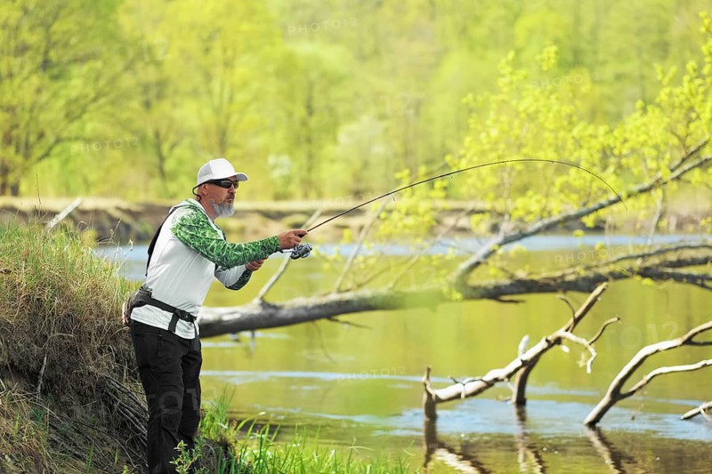 Fisherman trying to do a perfect cast, throwing lure. Spining fishing, angling, catching fish. Hobby and vacation. Photo with shallow depth of field taken at wide open aperture