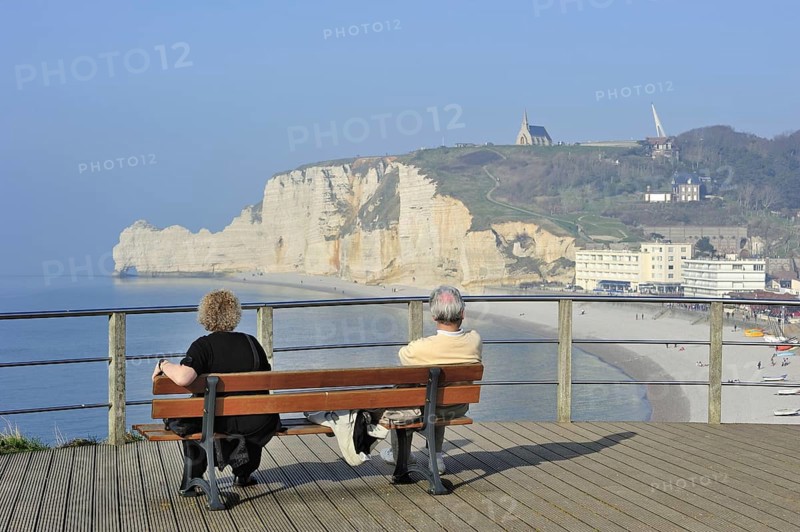 Elderly tourists looking at the chalk cliff Porte d'Amont and the chapel Notre-Dame-de-la-Garde at Etretat, Côte d'Albâtre, Upper Normandy, France, Europe