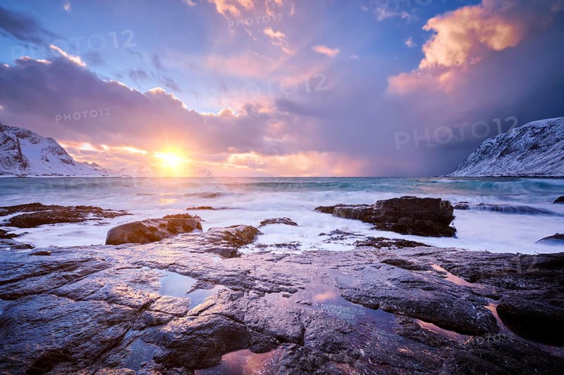 Beach of Norwegian sea on rocky coast in fjord on sunset in winter. Vareid beach, Lofoten islands, Norway, Europe