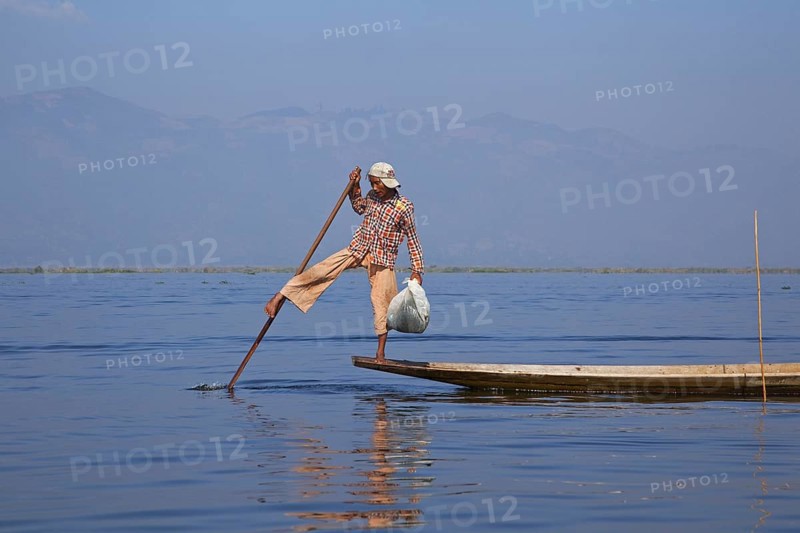 Intha fisherman steering traditional fishing boat by wrapping his leg around the oar, Inle Lake, Nyaungshwe, Shan State, Myanmar, Burma, Asia