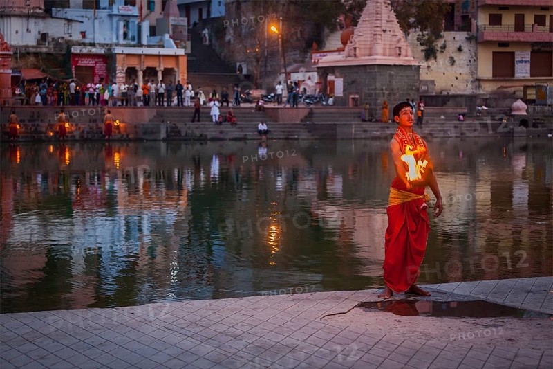 UJJAIN, INDIA, APRIL 23, 2011: Brahmin performing Aarti pooja ceremony on bank of holy river Kshipra. Aarti is Hindu religious ritual of worship, part of puja when light is offered to one or more deities