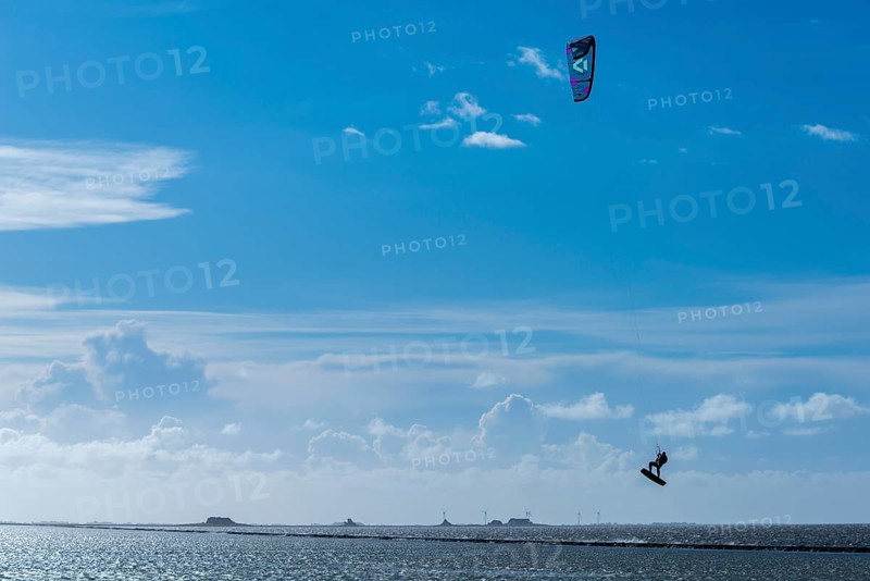 Kitesurfing on the North Sea, Lüttmoorsiel, Reußenköge, on the horizon Hallig Nordstrandischmoor, Lorendamm, wind power, wind force 6, blue sky, North Frisia, Schleswig-Holstein, Germany, Europe