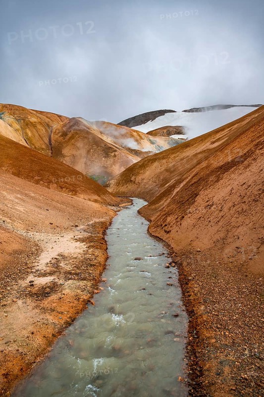 Steaming stream between colourful rhyolite mountains and snowfields, Hveradalir geothermal area, Kerlingarfjöll, Icelandic Highlands, Iceland, Europe