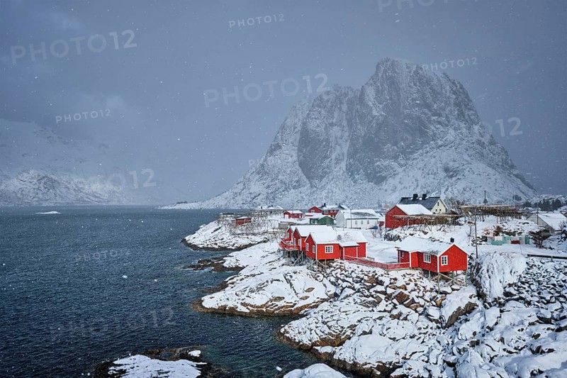 Iconic Hamnoy fishing village on Lofoten Islands, Norway with red rorbu houses. With falling snow in winter