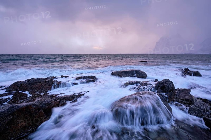 Beach of Norwegian sea on rocky coast in fjord on sunset in winter. Vareid beach, Lofoten islands, Norway, Europe