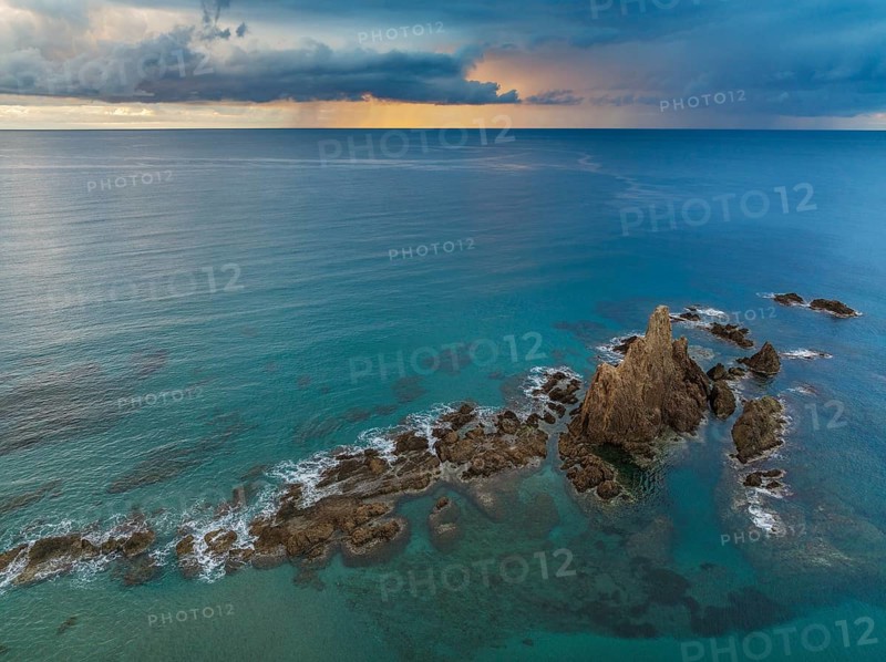 The reef Arrecife de las Sirenas in the Nature Reserve Cabo de Gata-Nijar, at sunrise with heavy showers in the distance, aerial view, drone shot, Almería province, Andalusia, Spain, Europe