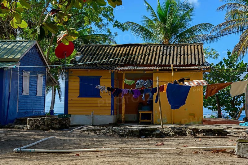 A colourful beach house with laundry on the line surrounded by palm trees under a blue sky, Bayahibe, Dominican Republic, Hispaniola, Caribbean, America, Central America