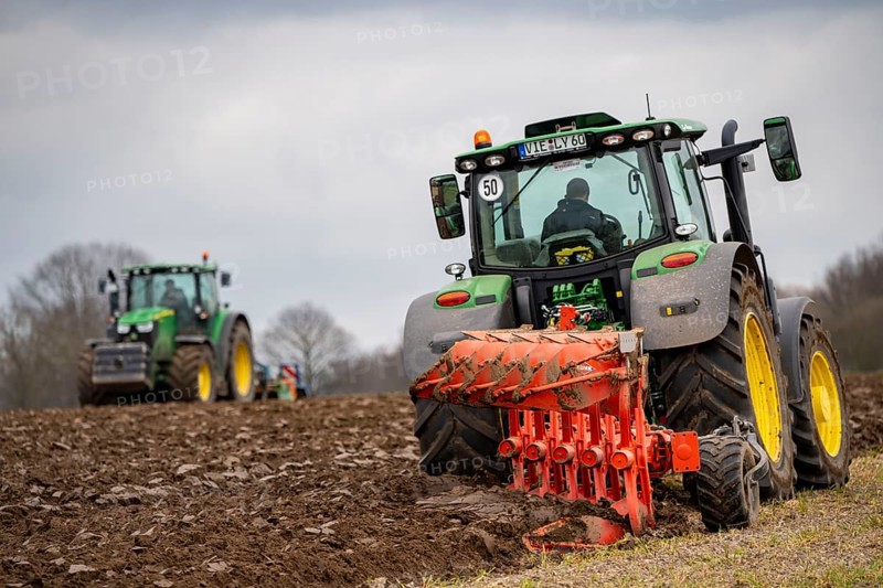 Tractor with a plough preparing the soil of a field for planting, Agriculture, Spring