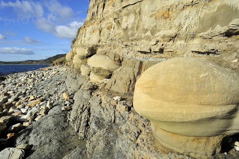 Rounded nodules on the beach near Osmington Mills, made of calcite-cemented sandstone, come from the Bencliff Grit Formation along the Jurassic Coast, Dorset, southern England, UK
