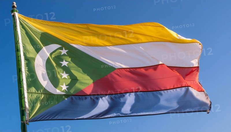 The flag of the Comoros flutters in the wind, isolated against a blue sky