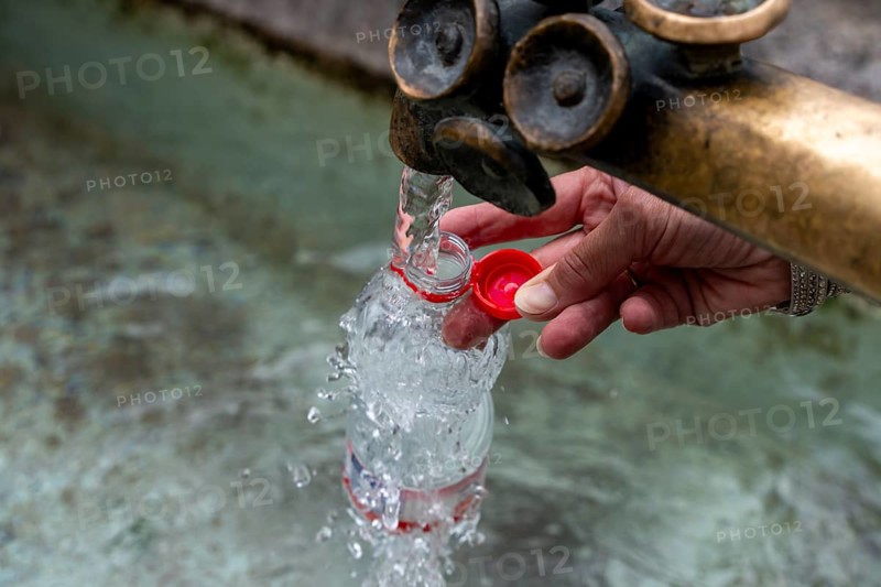 Water fountain, a woman fills drinking water into a small plastic bottle, Munich, Bavaria, Germany, Europe