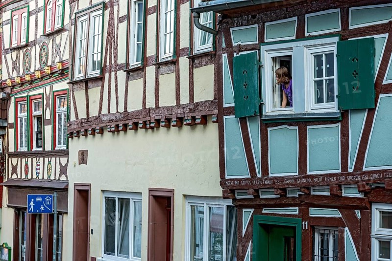 Historic medieval half-timbered houses, row of houses, girl looking out of window onto play street, old town, Friedberg, Wetterau, Hesse, Germany, Europe