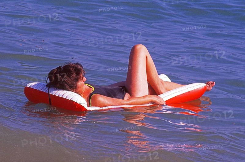Woman lies on an air mattress in the water in Calella, Costa Brava, Barselona, ??Catalonia, Spain, Southern Europe. Scanned thumbnail slide, vintage, retro, funny, Europe